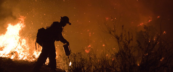 Graphic showing a firefighter walking near flames in a wildfire