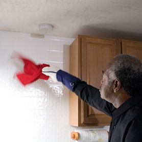 Graphic showing a man dusting a wall below a smoke alarm