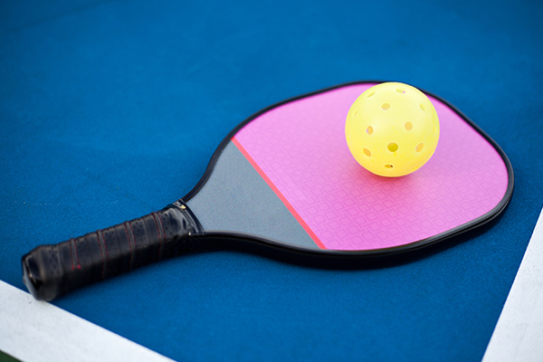 a pickleball paddle and whiffle ball