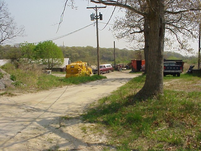 image 46a - a dirt road leads to a building with trucks and heavy duty work vehicles